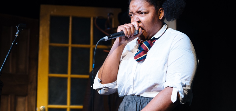 Young woman in school uniform speaking into microphone.